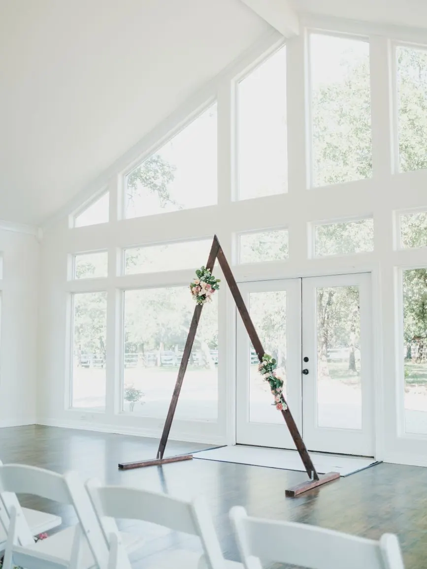Arche florale ivoire dressée pour une cérémonie de mariage en jardin au coucher du soleil