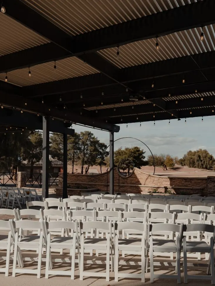 Longues tables sous guirlandes lumineuses pour un dîner de mariage en plein air