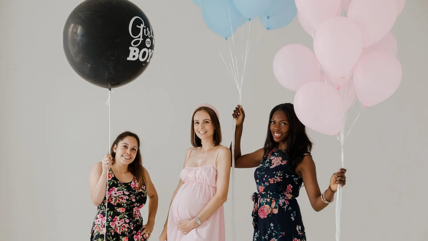 Ballon de gender reveal éclaté libérant des confettis roses devant les invitées