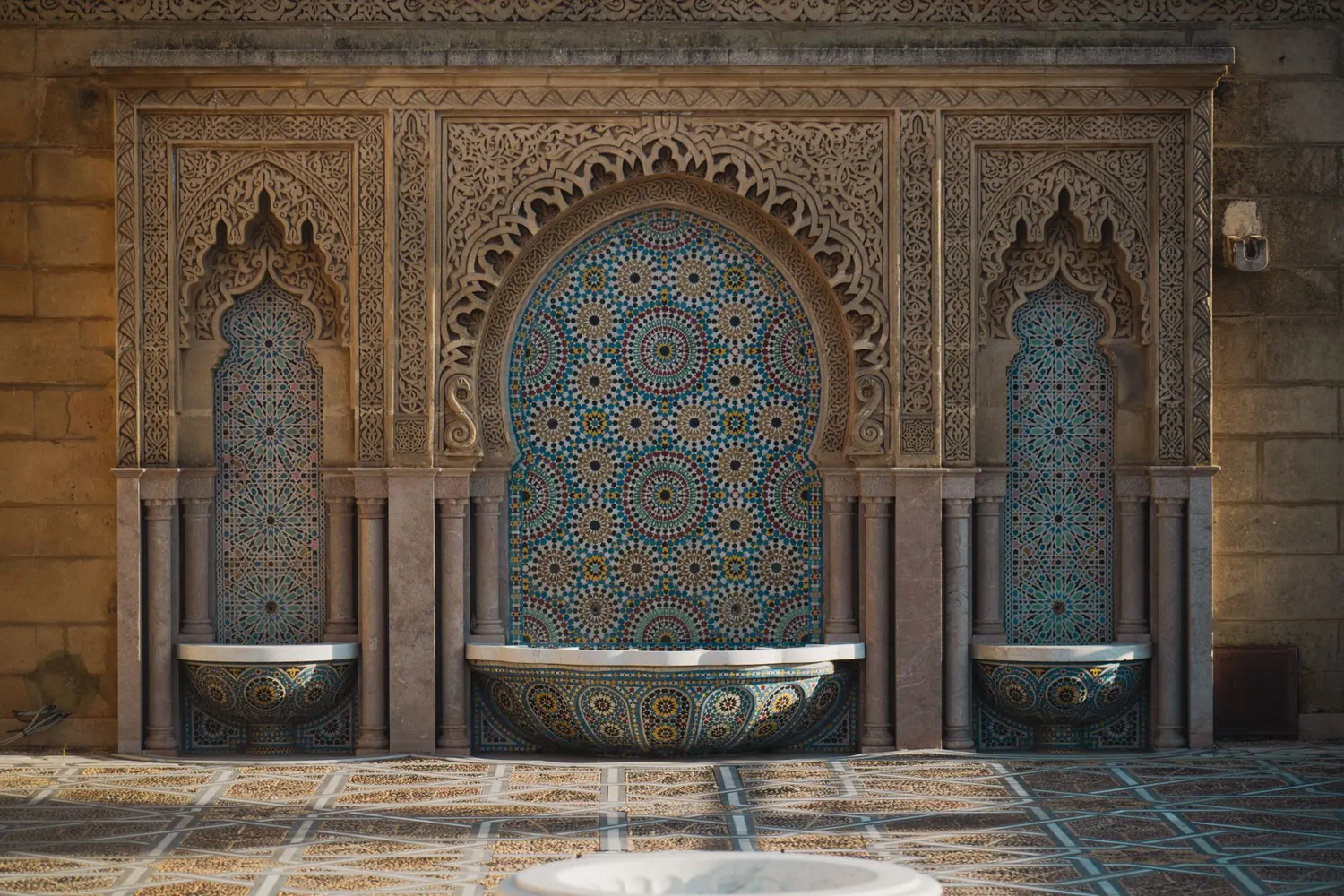 Patio de riad aux zelliges avec fontaine centrale fleurie dans la médina de Marrakech